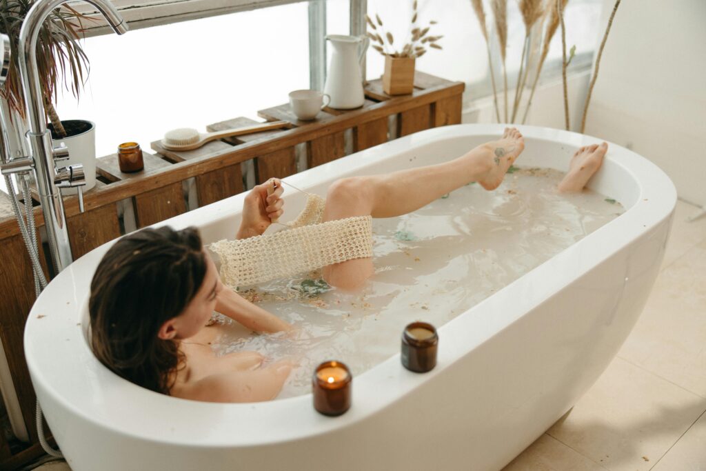 A serene moment of relaxation in a bathtub surrounded by warm candlelight indoors.